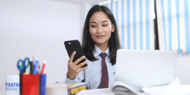 Student holding smart phone around books and tables