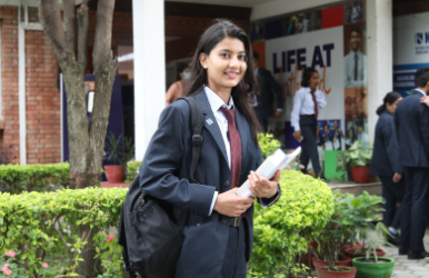 Student walking on campus with books in hand at Kathford College