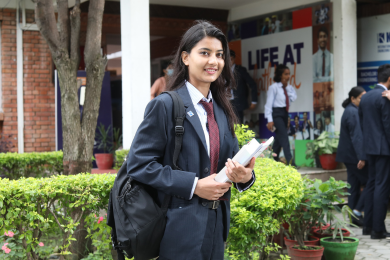 Student walking on campus with books in hand at Kathford College