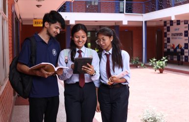 Group of students carrying books and tablets outdoors in the college premises