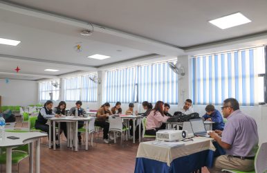 Students working on business writing tasks during a classroom workshop session.
