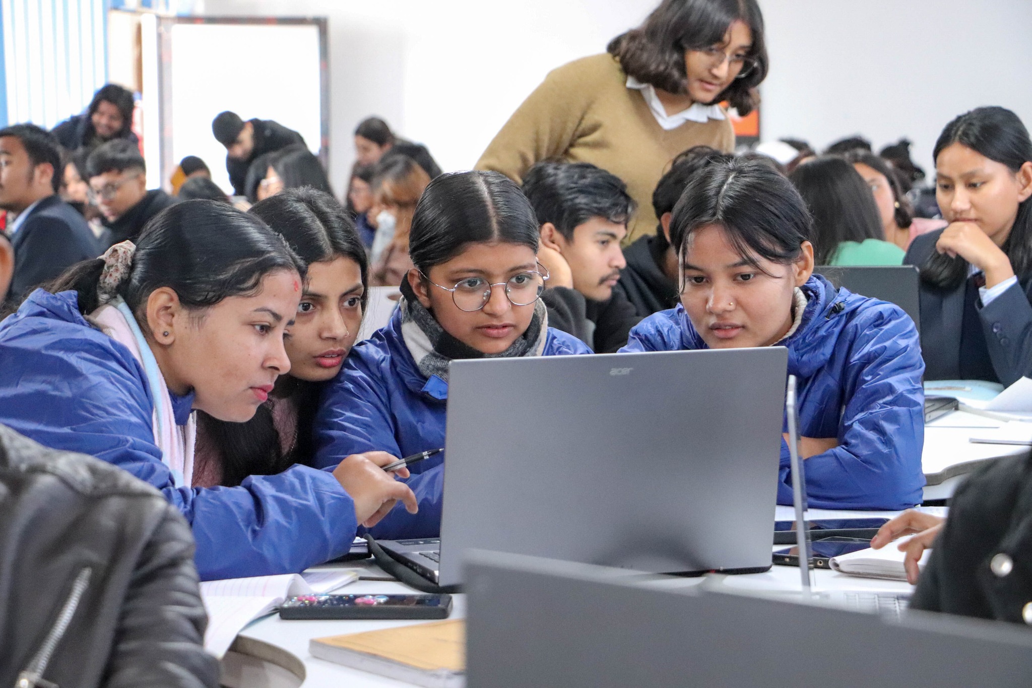 Students working together on a laptop during an AI session.